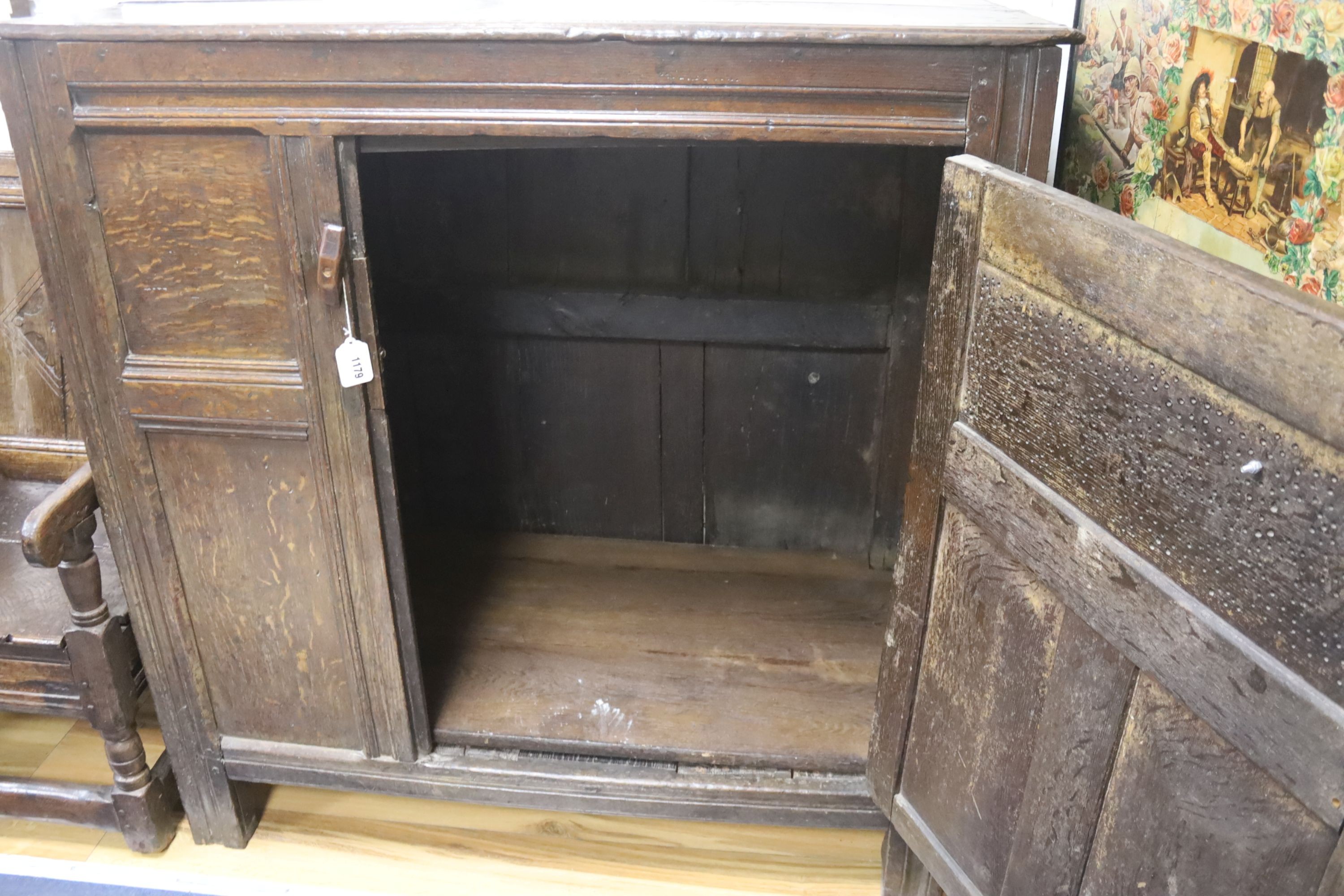 An early joined oak food cupboard, the planked top above a single hinged pierced panelled door, width 112cm, depth 55cm, height 115cm